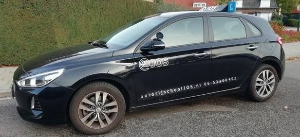 De lesauto van Autorijschool @JOS, een zwarte Hyundai i30 met @JOS-belettering